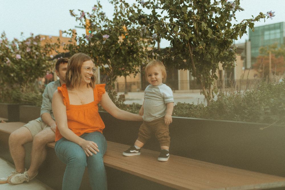 Group relaxing on outdoor bench near planters during sunset.