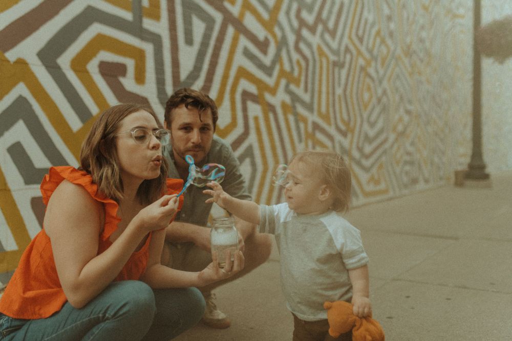 Family enjoying bubble play against an artistic geometric wall backdrop.