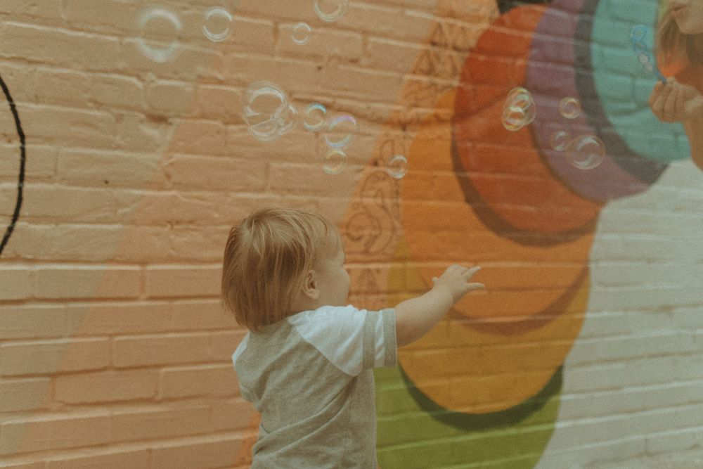 Small child points at colorful wall art with geometric shapes.
