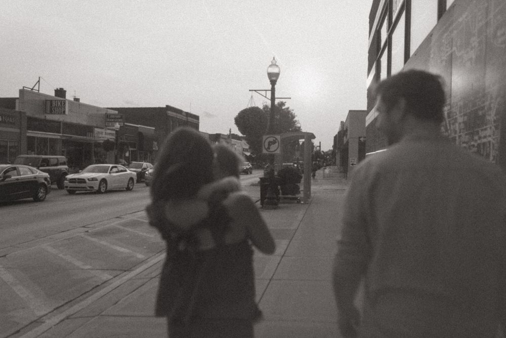 Black and white photo of people walking down city street at dusk.