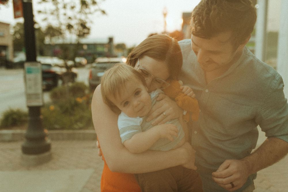 Family sharing tender embrace outdoors during golden hour.
