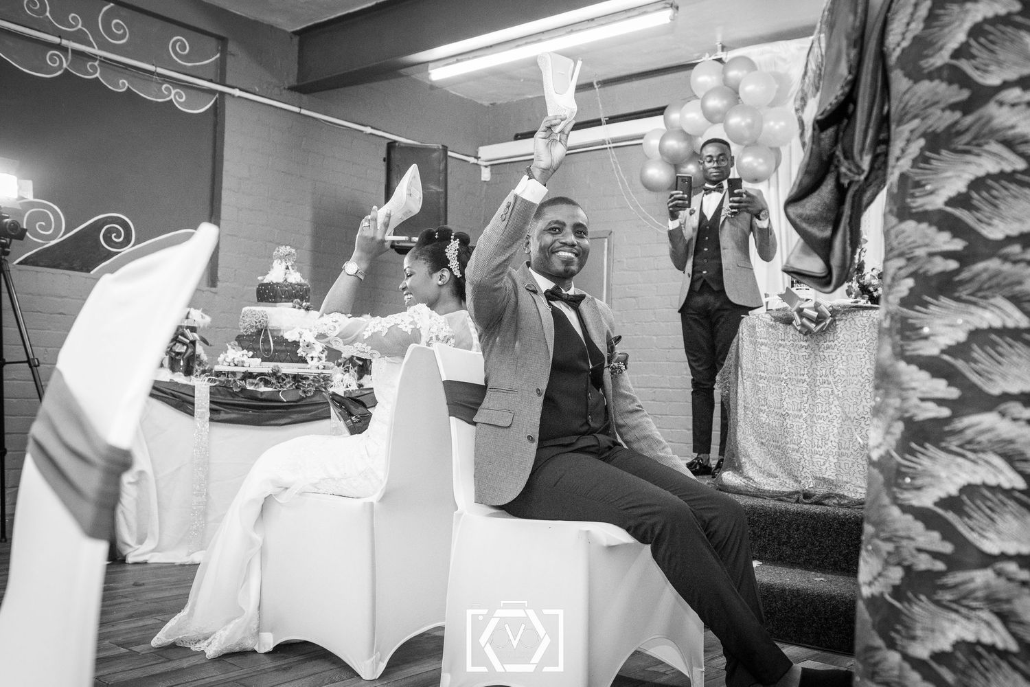 Man in suit raising his hand at a formal celebration event in black and white photography.