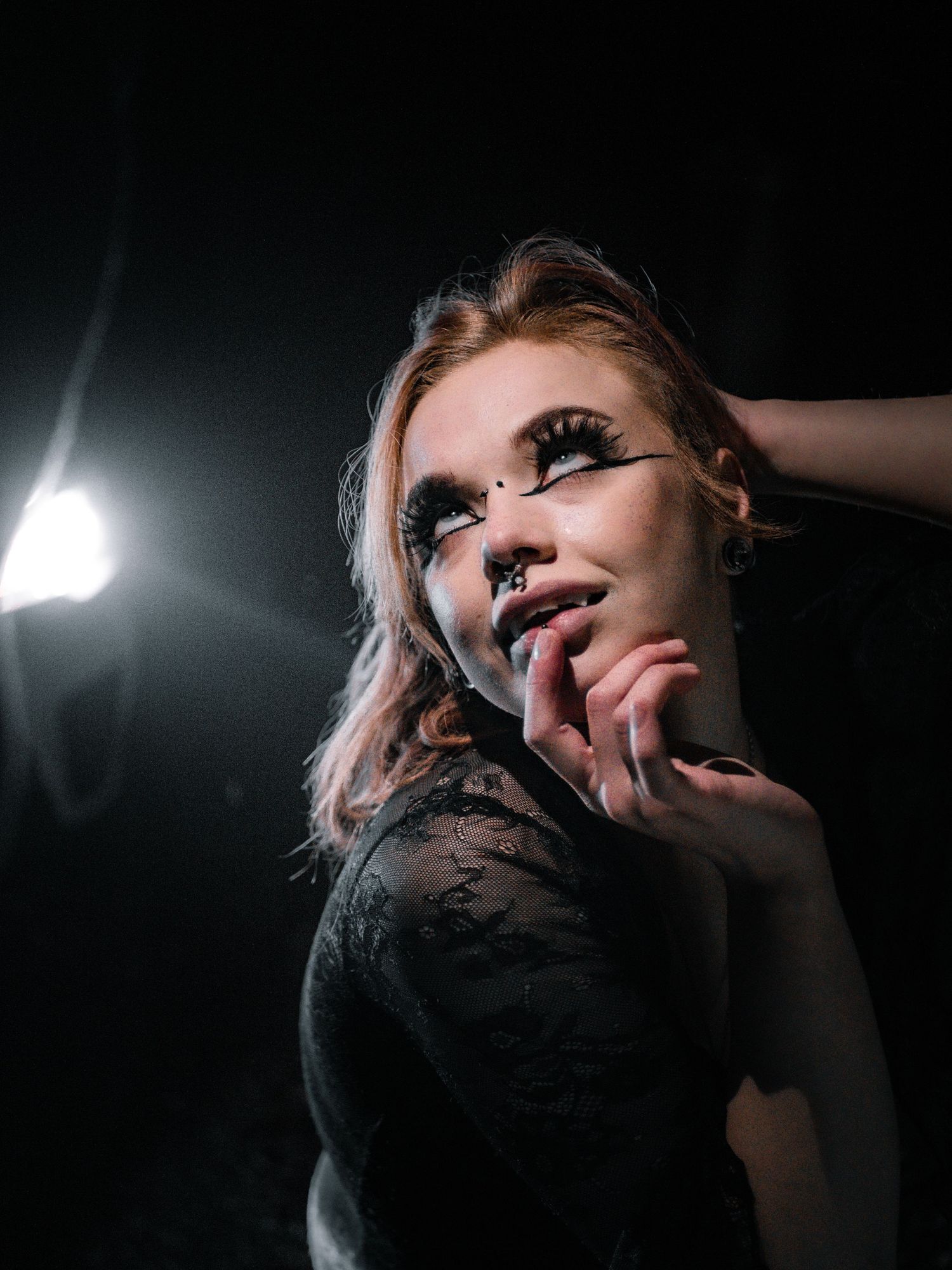 Dramatic low-light portrait with artistic makeup and moody lighting effects.