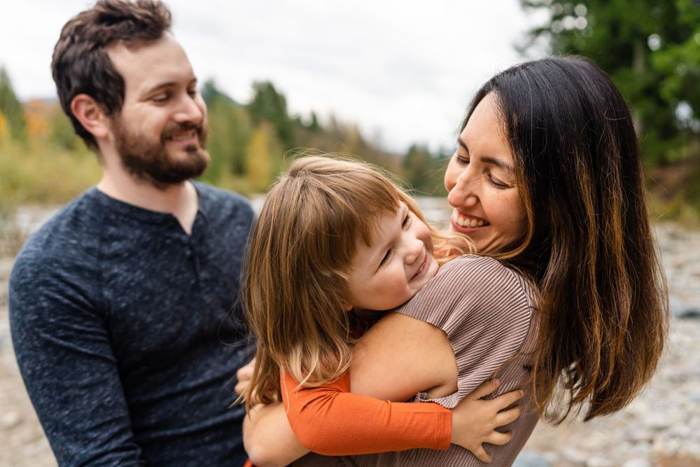 Parents laughing with their daughter by the river in North Bend.