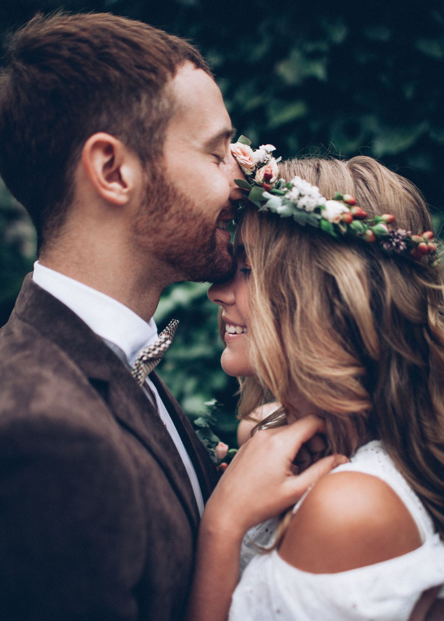 Romantic wedding moment captured in natural outdoor setting with floral crown details.