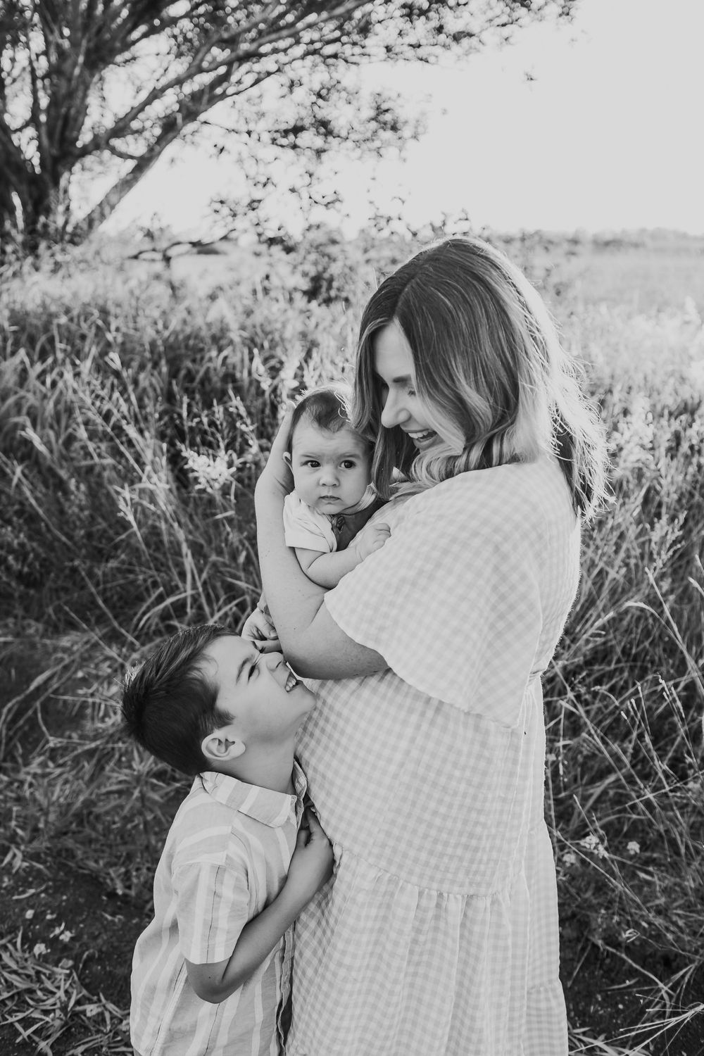 A touching black and white portrait of a family embracing outdoors.
