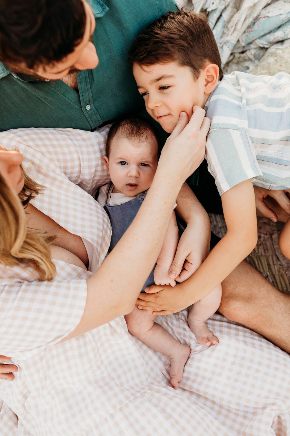 An intimate family moment captured on a blanket outdoors.