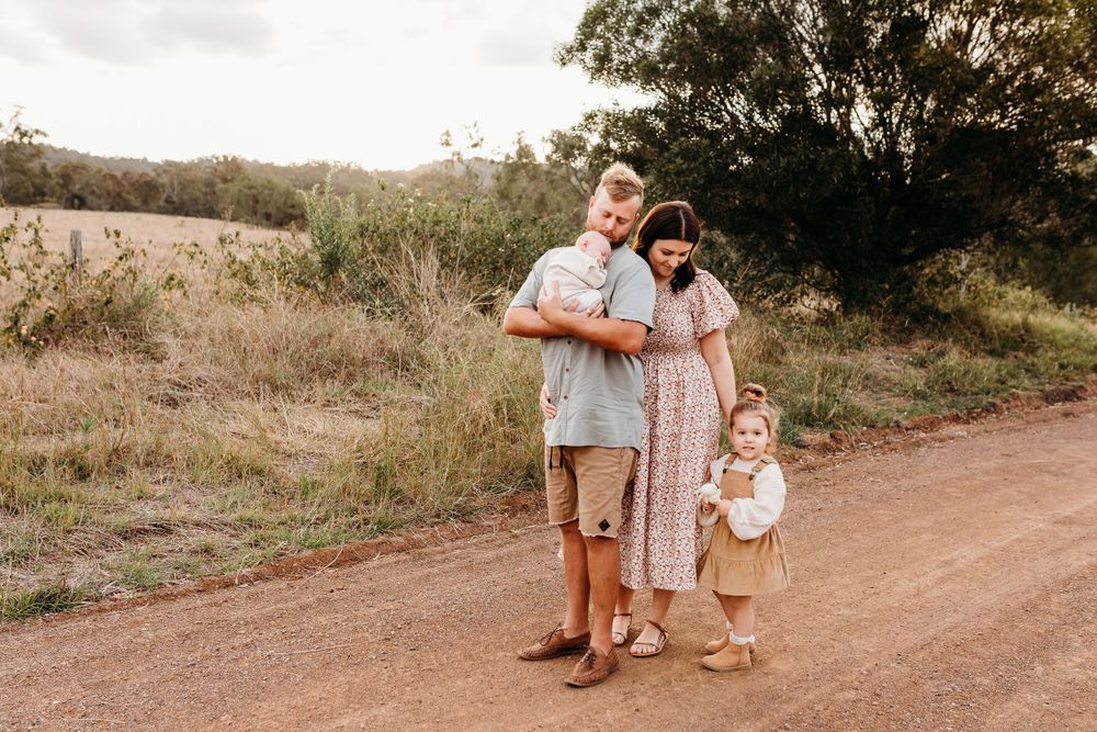 A family stands together on a rustic dirt path at sunset.