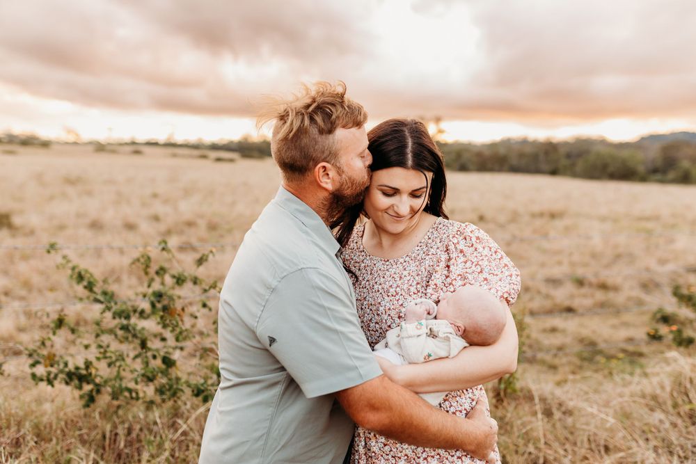 A tender family moment captured in a sun-drenched field during golden hour.