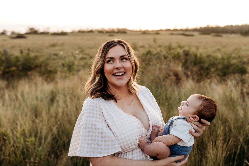 Candid family moments photographed in a rustic field during golden hour.
