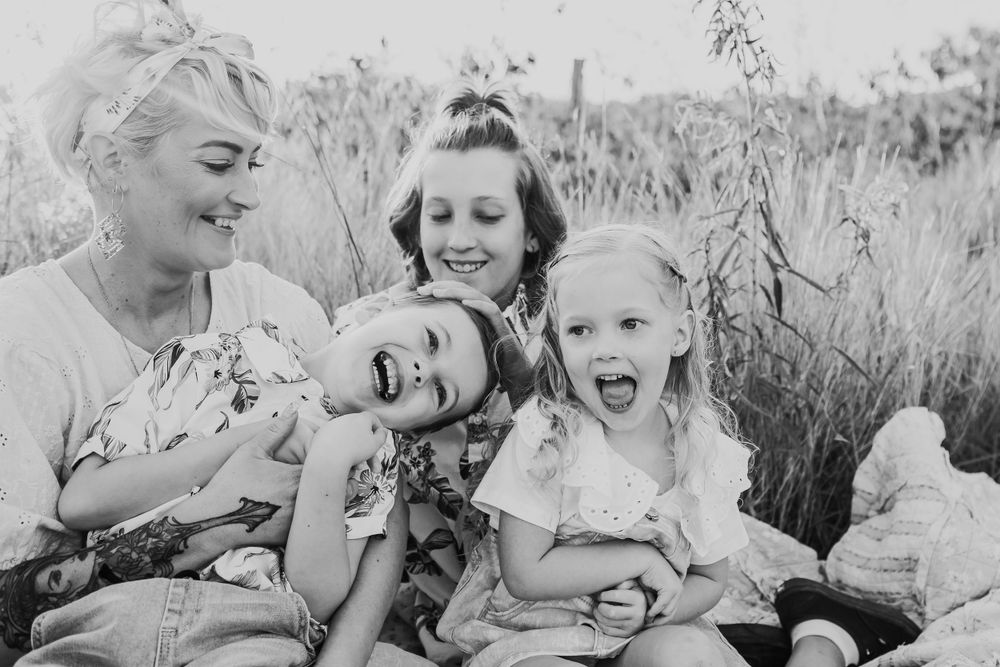 Joyful family photography session captured in tall grass during sunset.