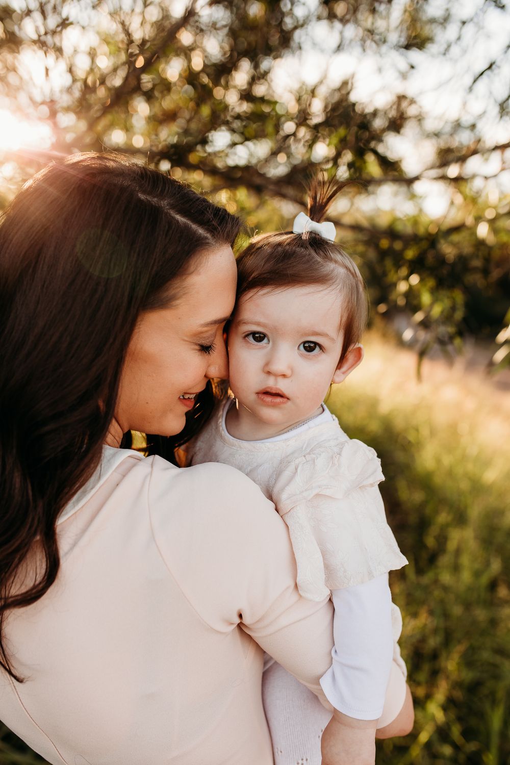 Intimate family portraits captured in golden sunlight among natural foliage.