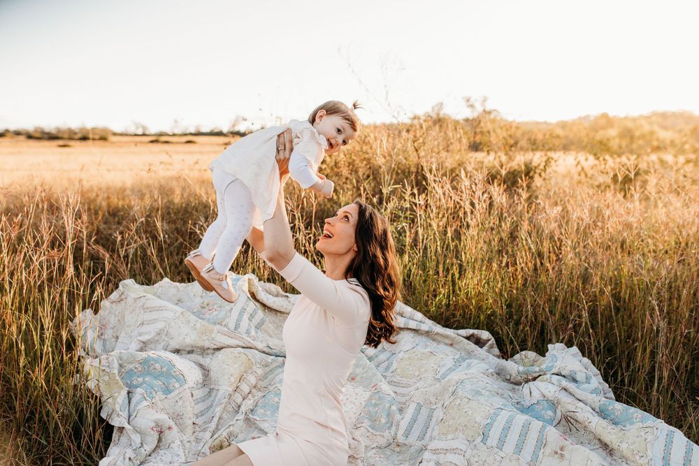 Family photography session in a sunlit field with flowing white dress.