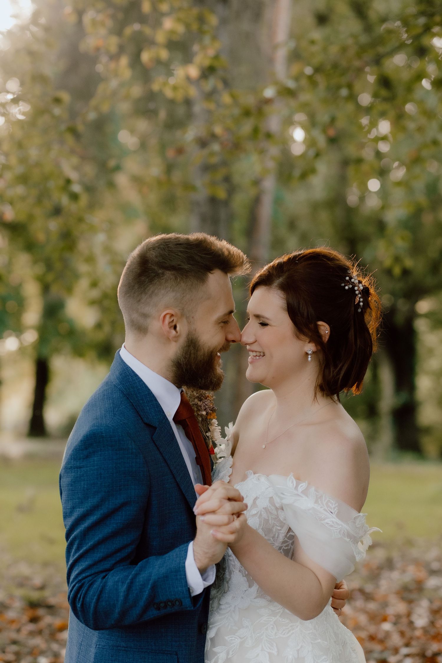 A tender moment between newlyweds dancing in a sunlit garden with fall foliage.