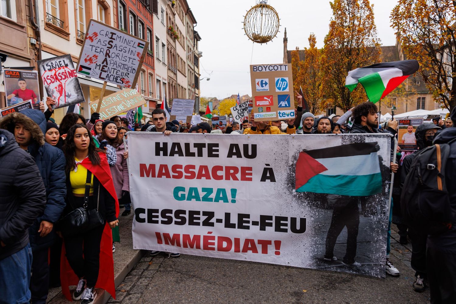 Street protest with demonstrators holding a large banner in French calling for cease-fire in Gaza.