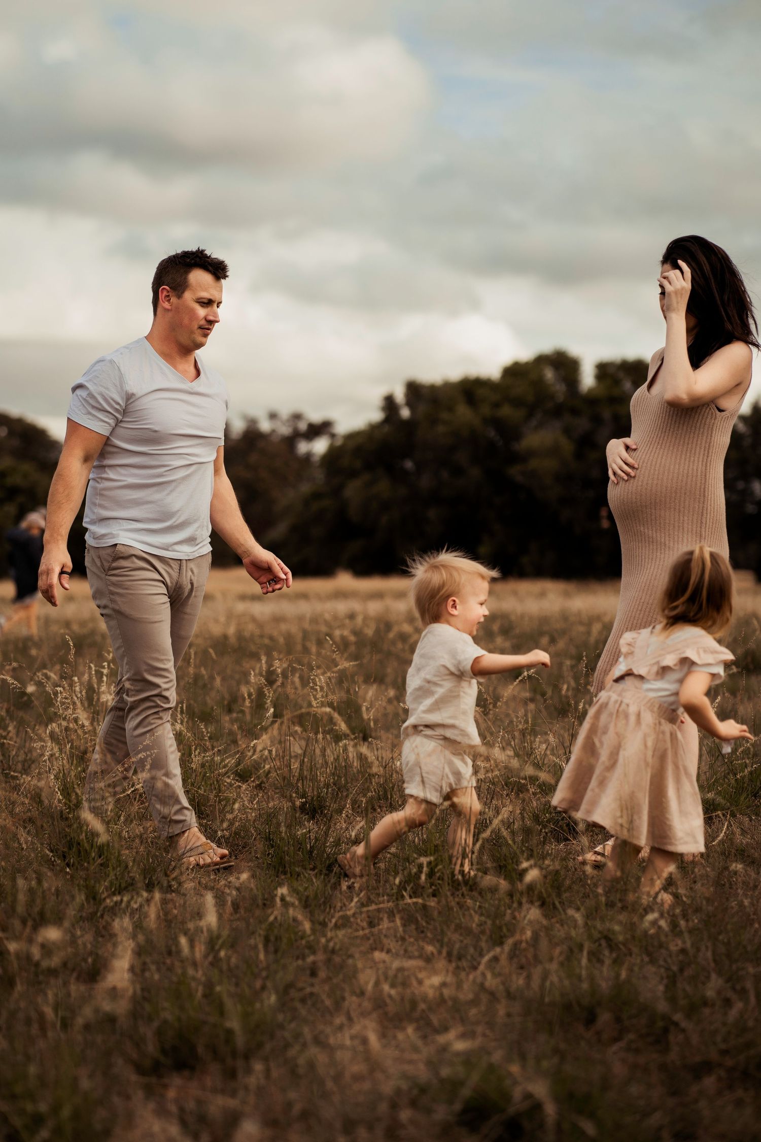 Family playing together in a rustic field during golden hour.
