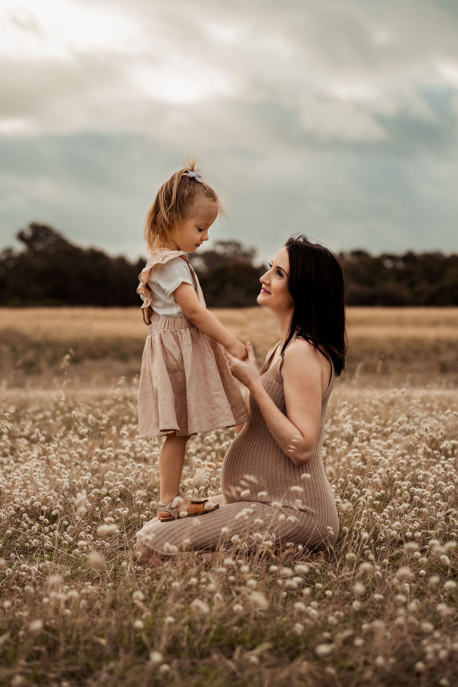 Mother and daughter share an intimate moment in a field of wildflowers.