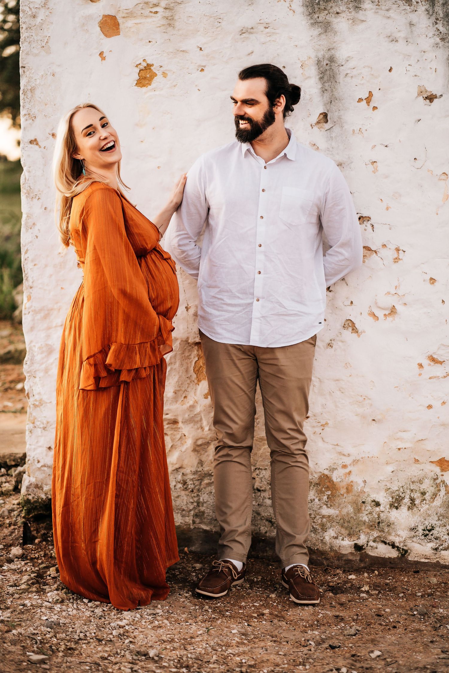 A joyful moment shared against a rustic white wall backdrop outdoors.