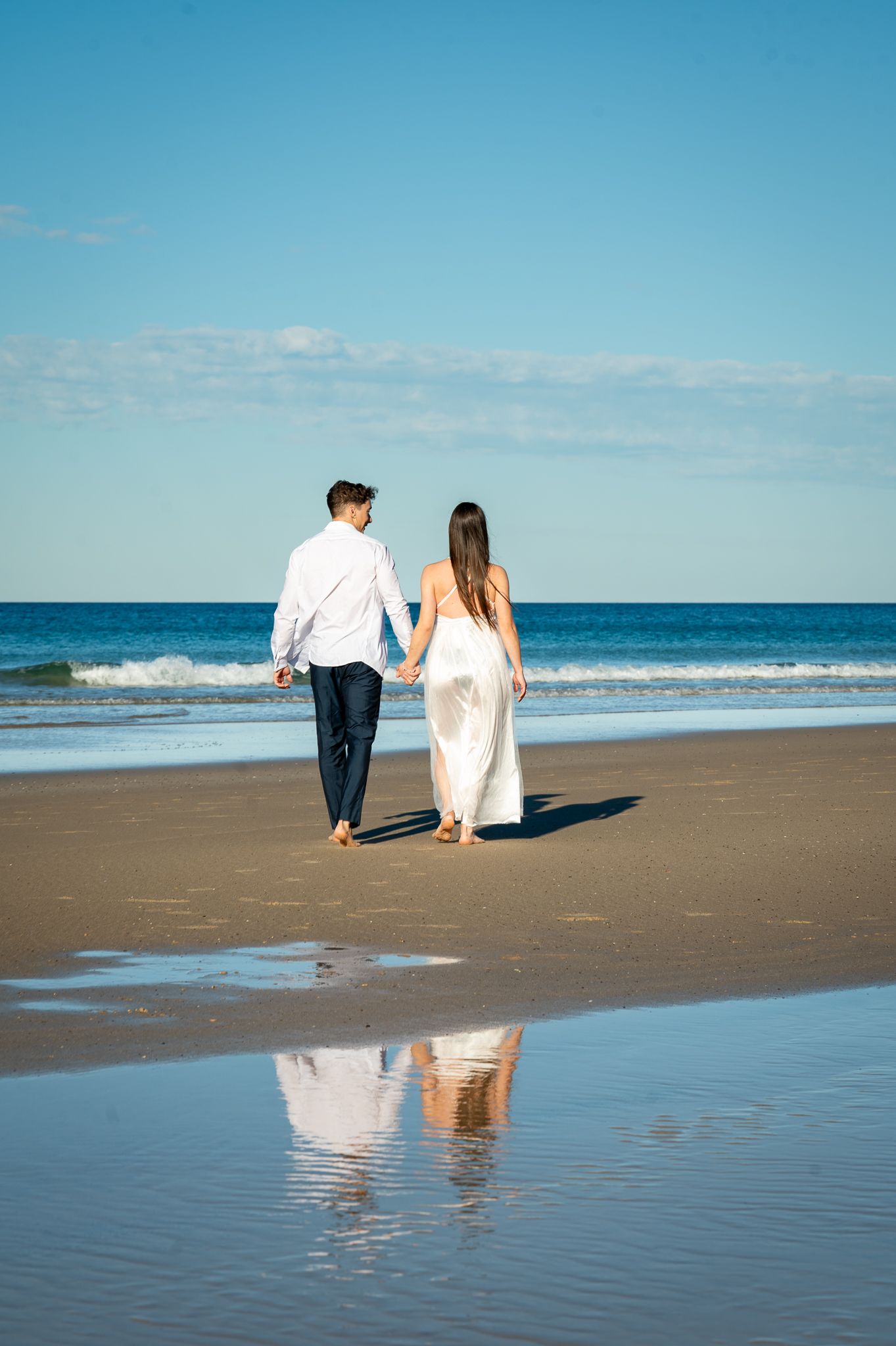 husband and wife walking on the beach in the sand
