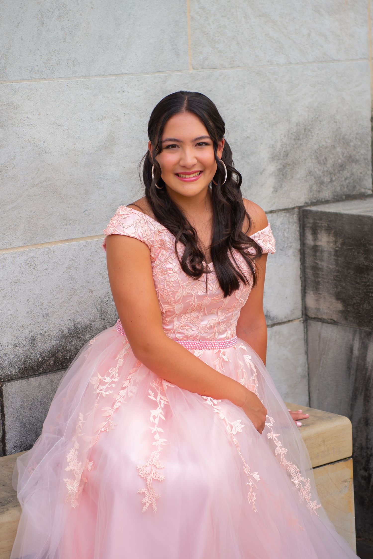 girl in pink gown seated at Mellon Park for quinceanera photos