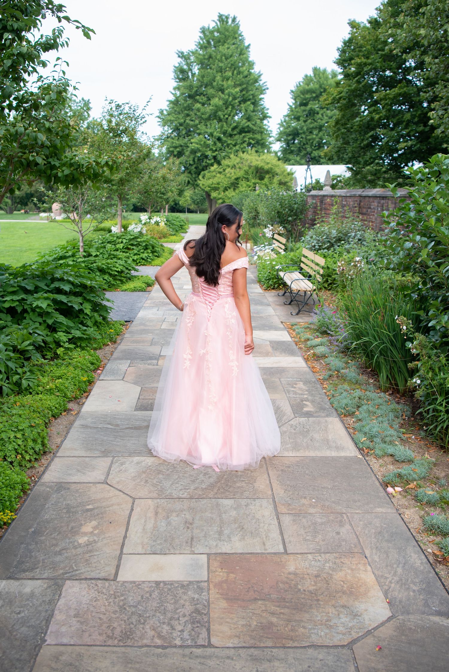 girl in pink ball gown walking on garden path at mellon park