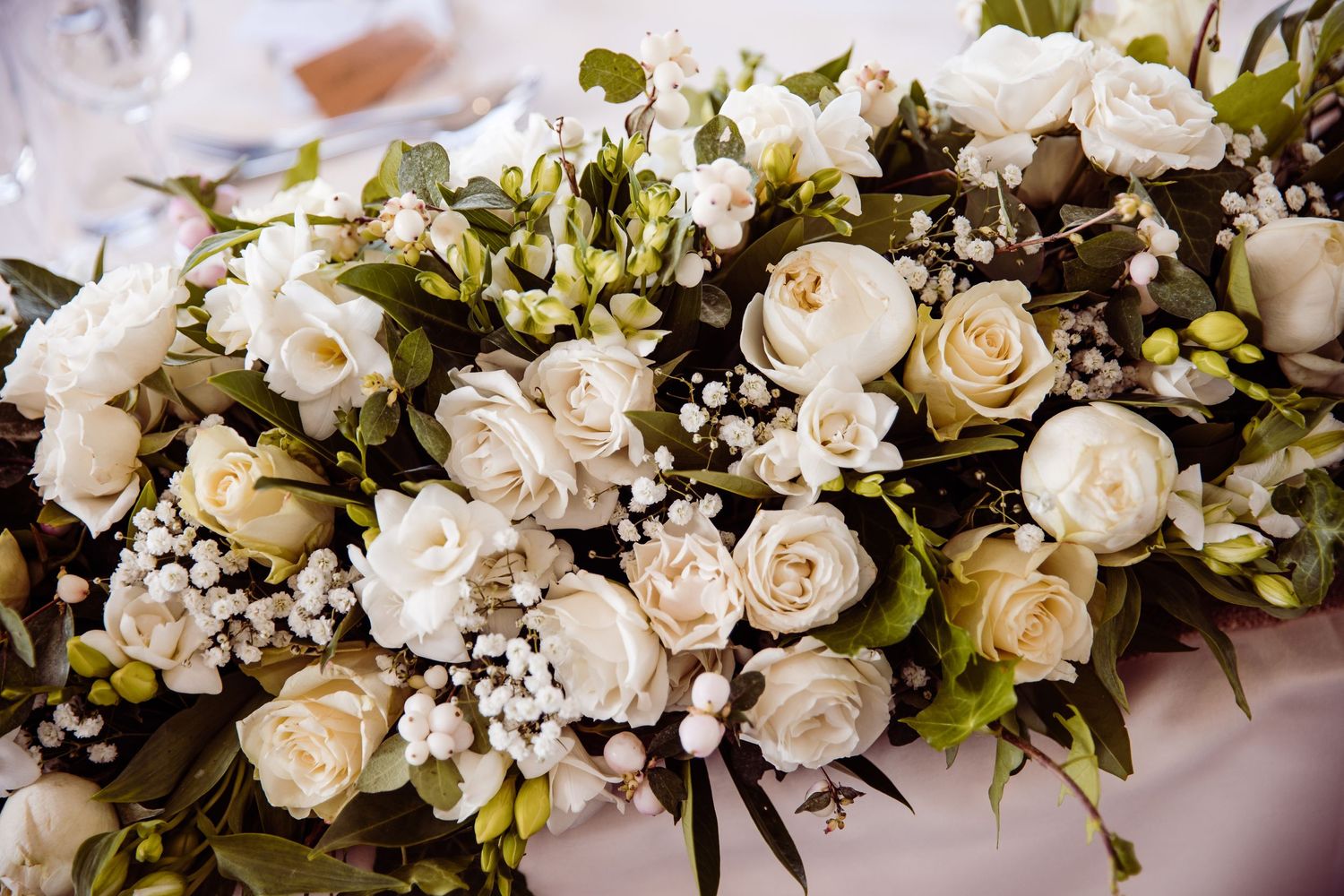Elegant white and cream floral wedding arrangement with roses and baby's breath.