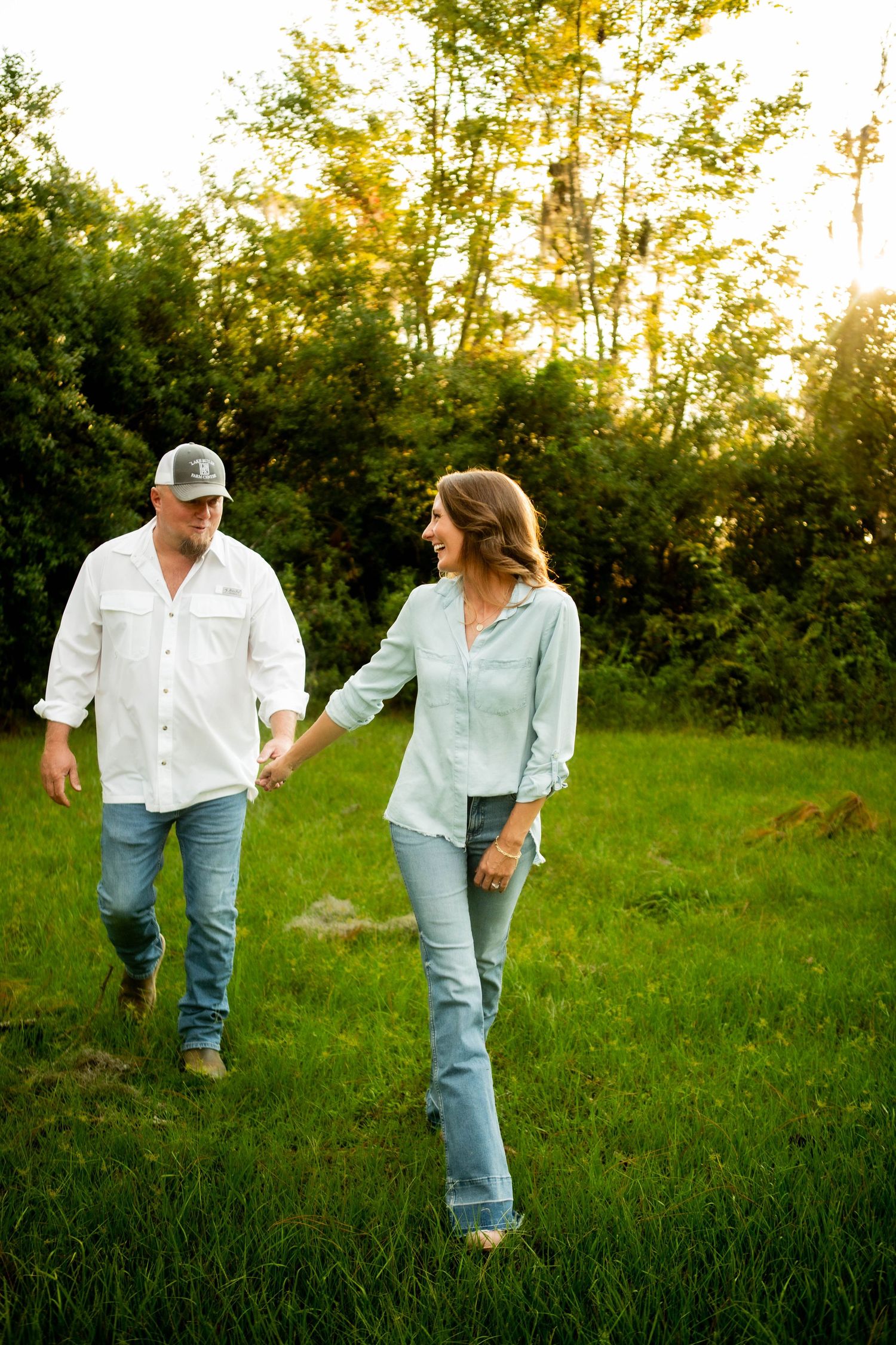 Couple walking together through sunny field at golden hour.