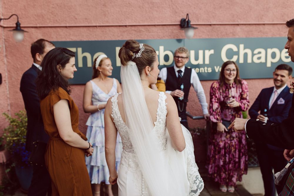 Wedding celebration with guests mingling in a warm-lit indoor venue.