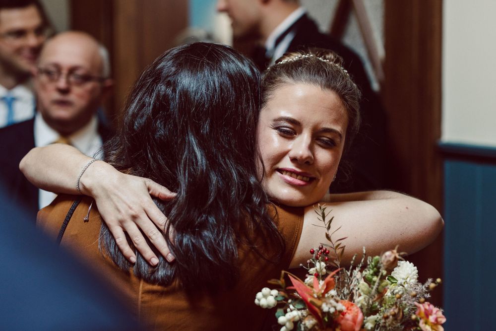 Guests sharing hugs and holding bouquets during a wedding celebration.