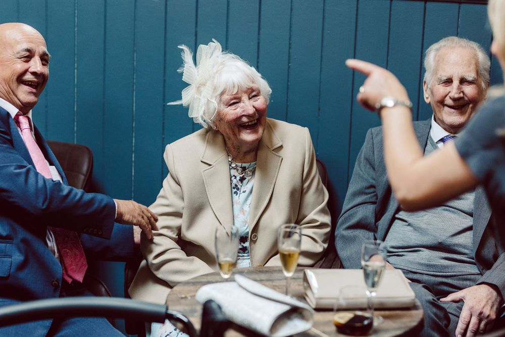 Guests sharing laughs while seated outdoors against a blue wall backdrop.