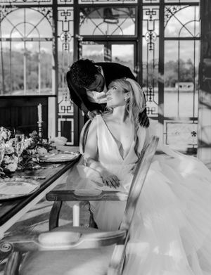 Black and white wedding photo inside an elegant vintage conservatory with ornate details.