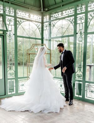 Wedding couple in an ornate mint green conservatory with dramatic natural lighting.