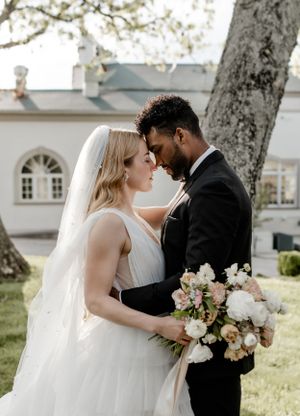 Romantic outdoor wedding portrait under a blooming tree with soft natural lighting.