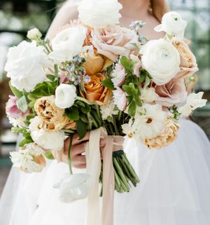 Elegant bridal bouquet featuring white and peach roses with delicate ribbon accents.