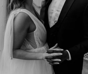 A black and white close-up detail shot of wedding rings and hands.