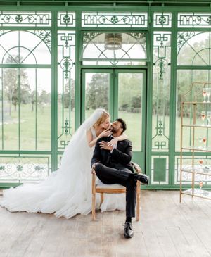 Romantic wedding scene with couple in elegant attire inside a mint green conservatory.