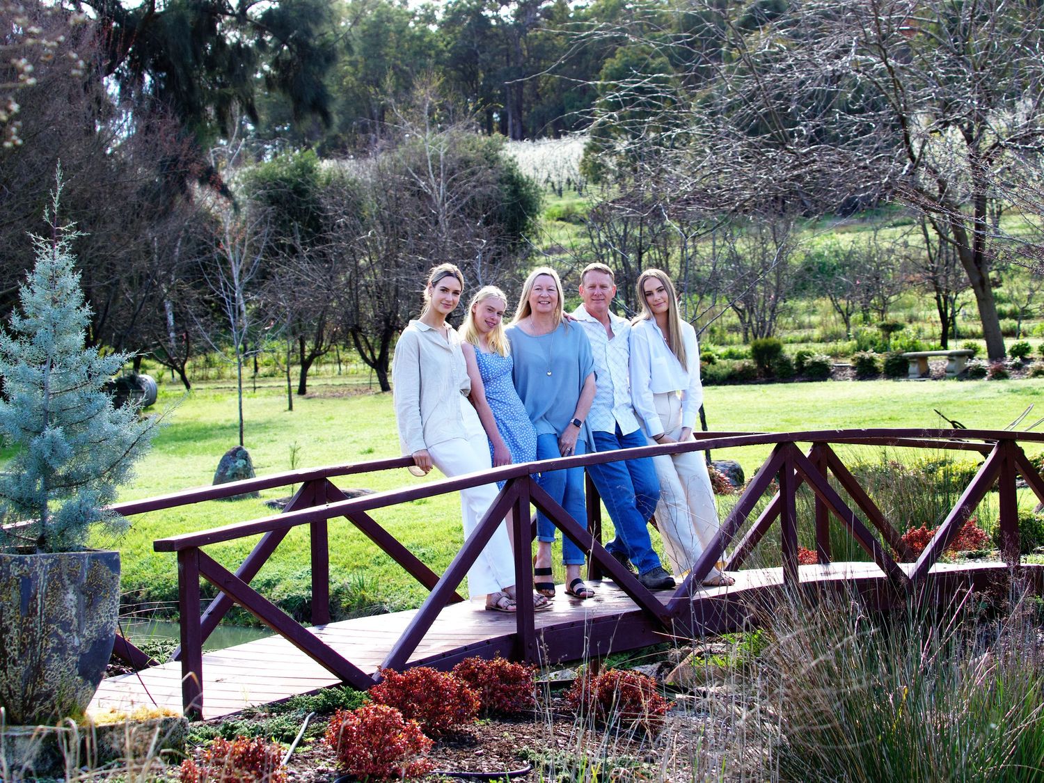 spring family portrait with mother father and three adult children wearing combinded colours of blue denium cream white