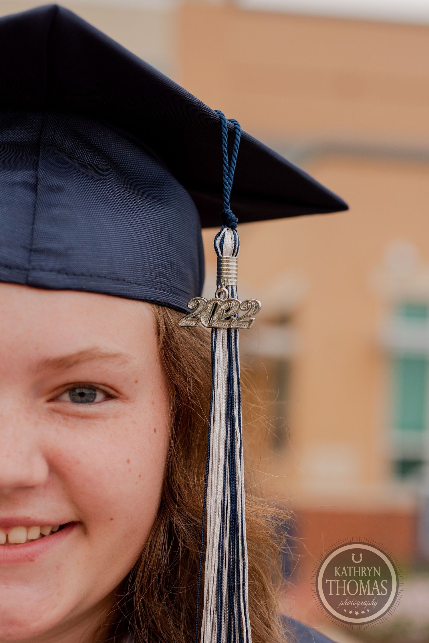 Close up detail of graduation cap tassel and decorative charm against school building.