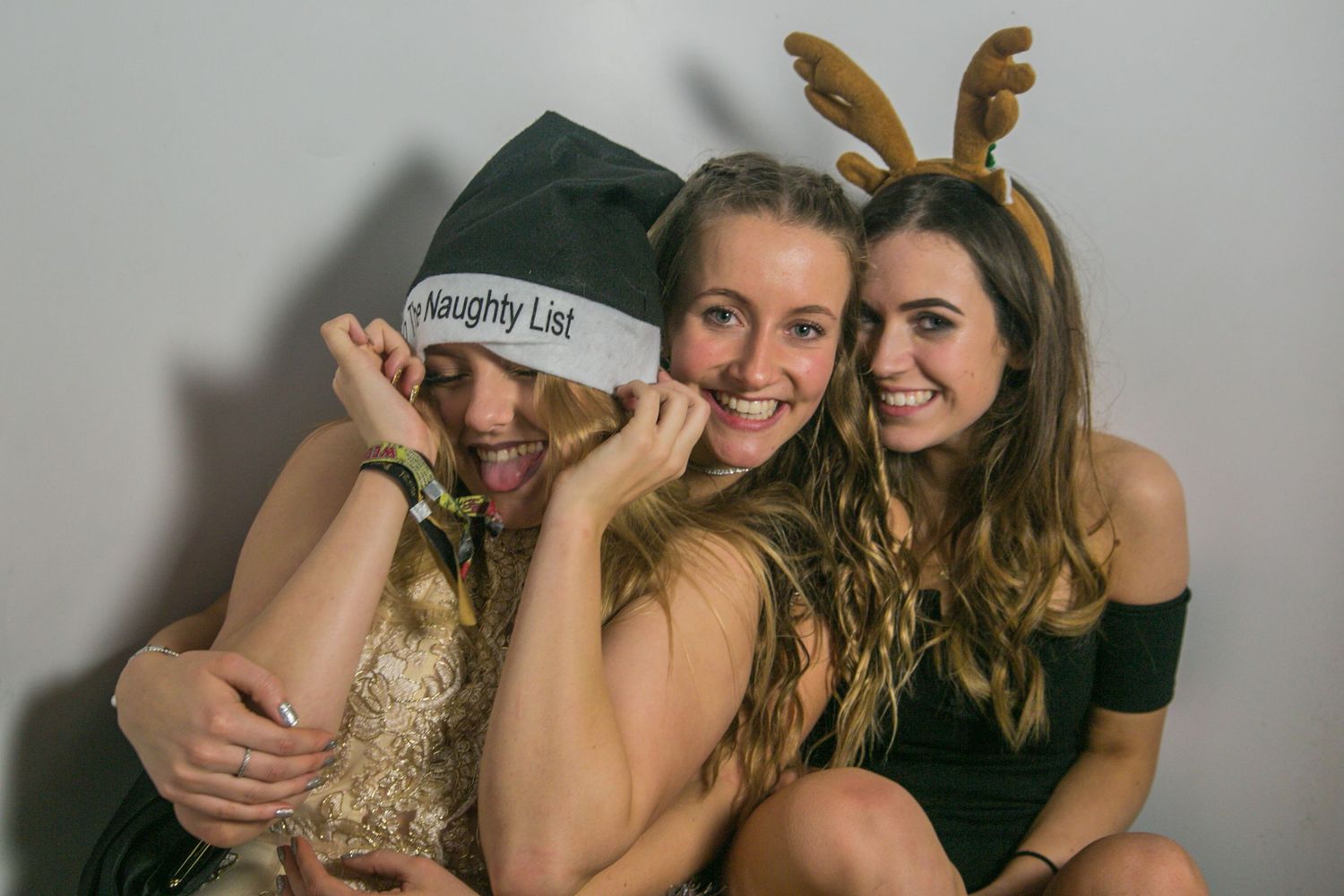 Group photo session with people wearing antler headbands against a gray background.