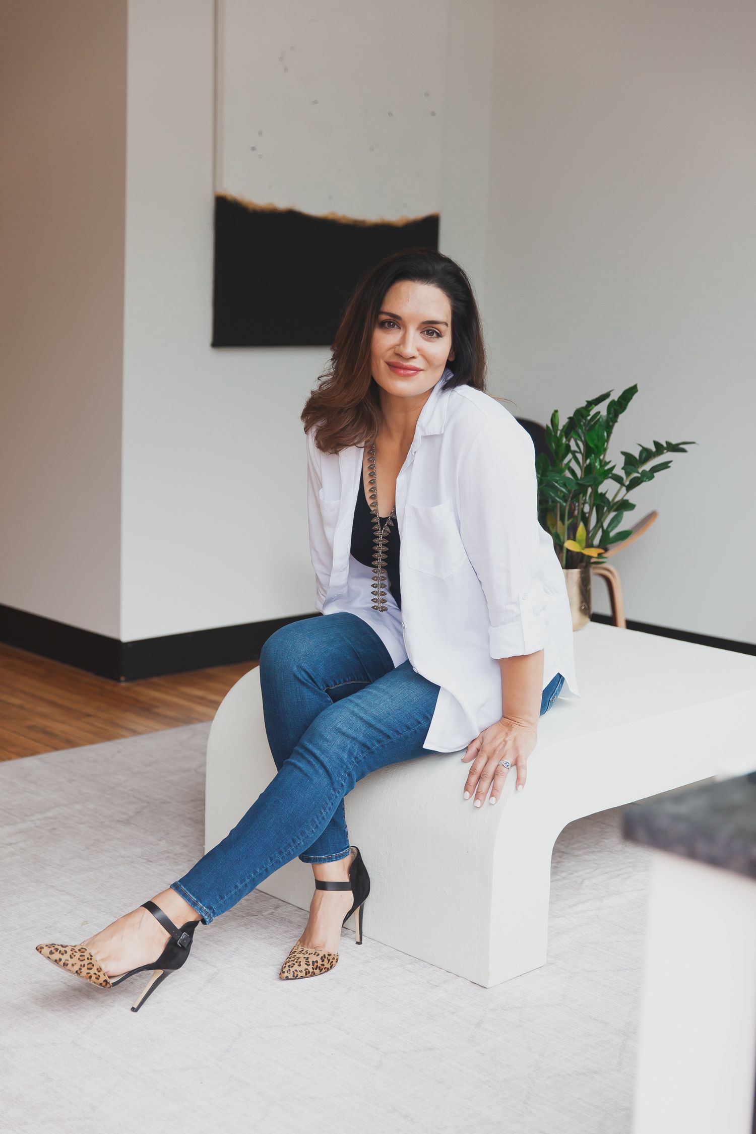 A joyful female business owner poses in front of her storefront, eager to connect with customers through Instagram.
