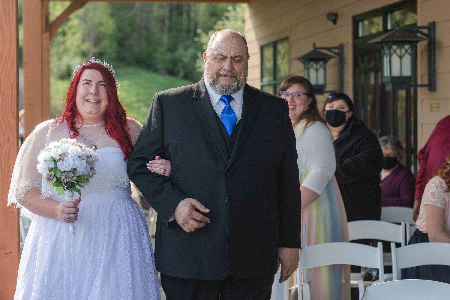 Wedding party members standing under a covered patio during an outdoor celebration.