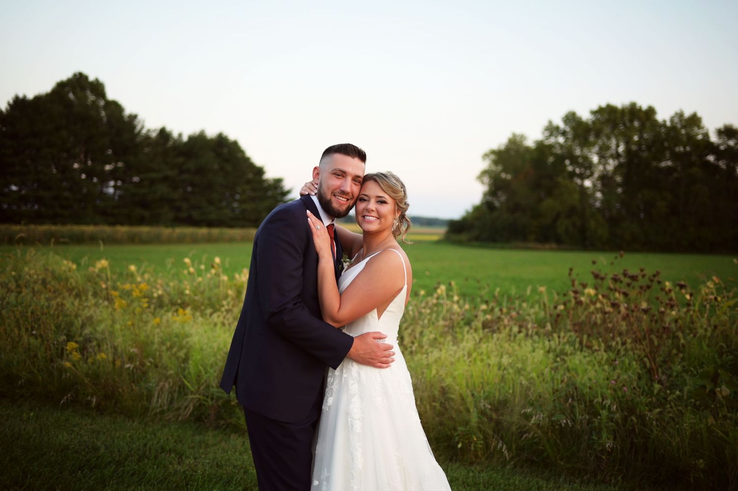 Romantic wedding portraits taken in a wildflower field during golden hour lighting.