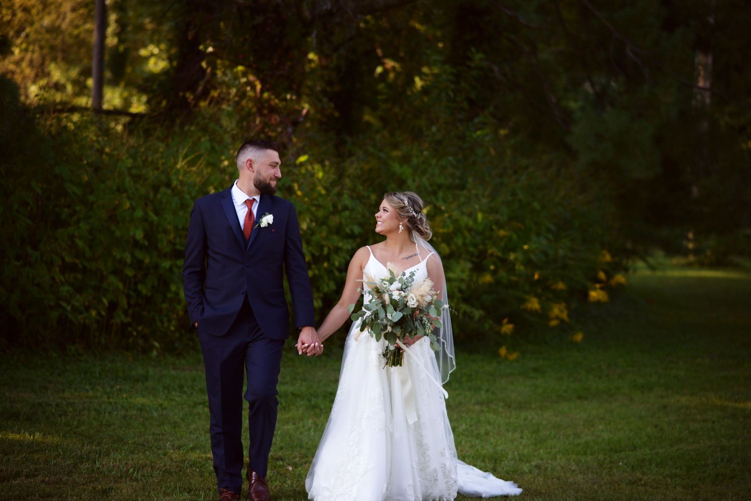 Bride and groom embrace while taking outdoor wedding photos at golden hour.
