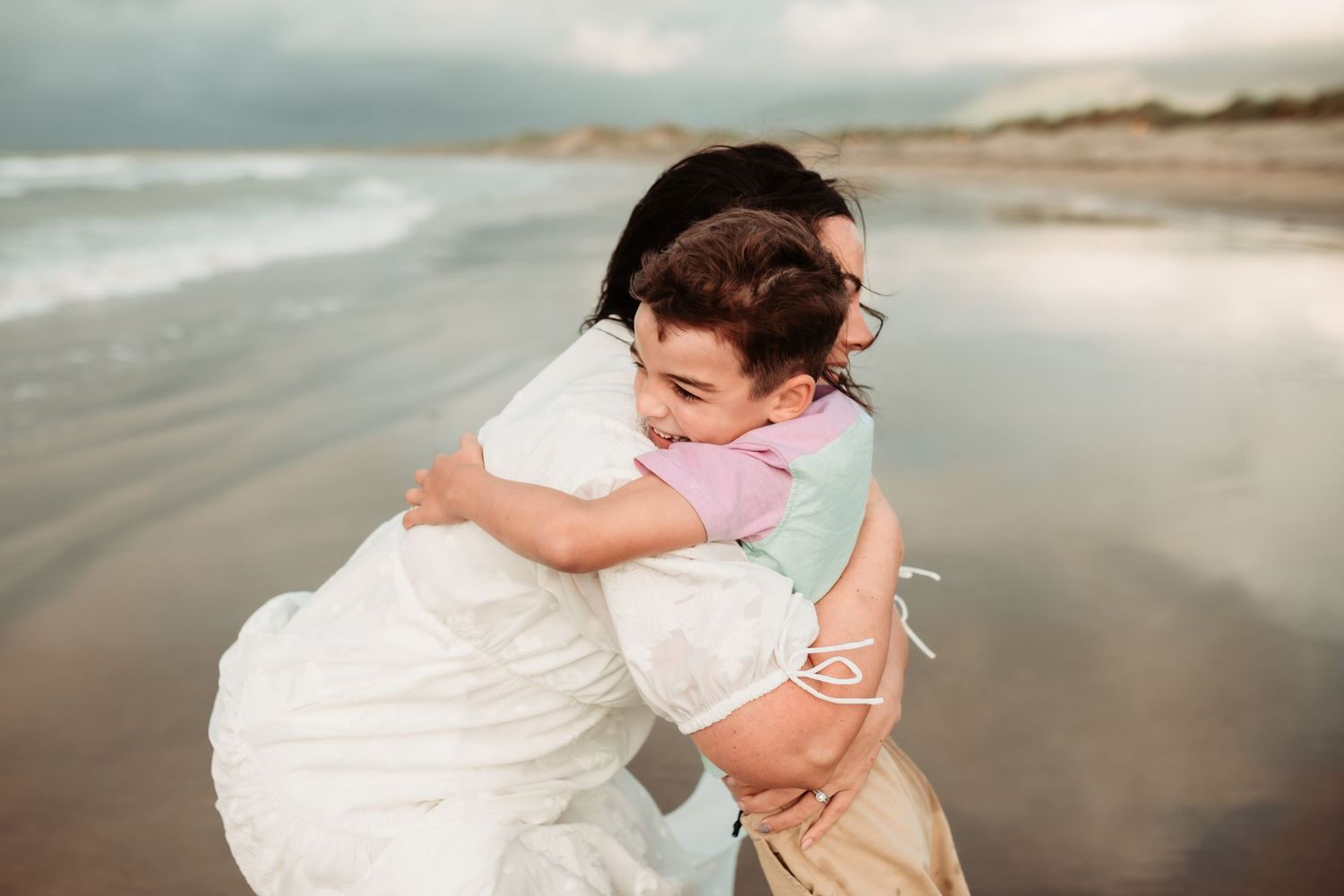 MUM HUGGING BOY ON BEACH