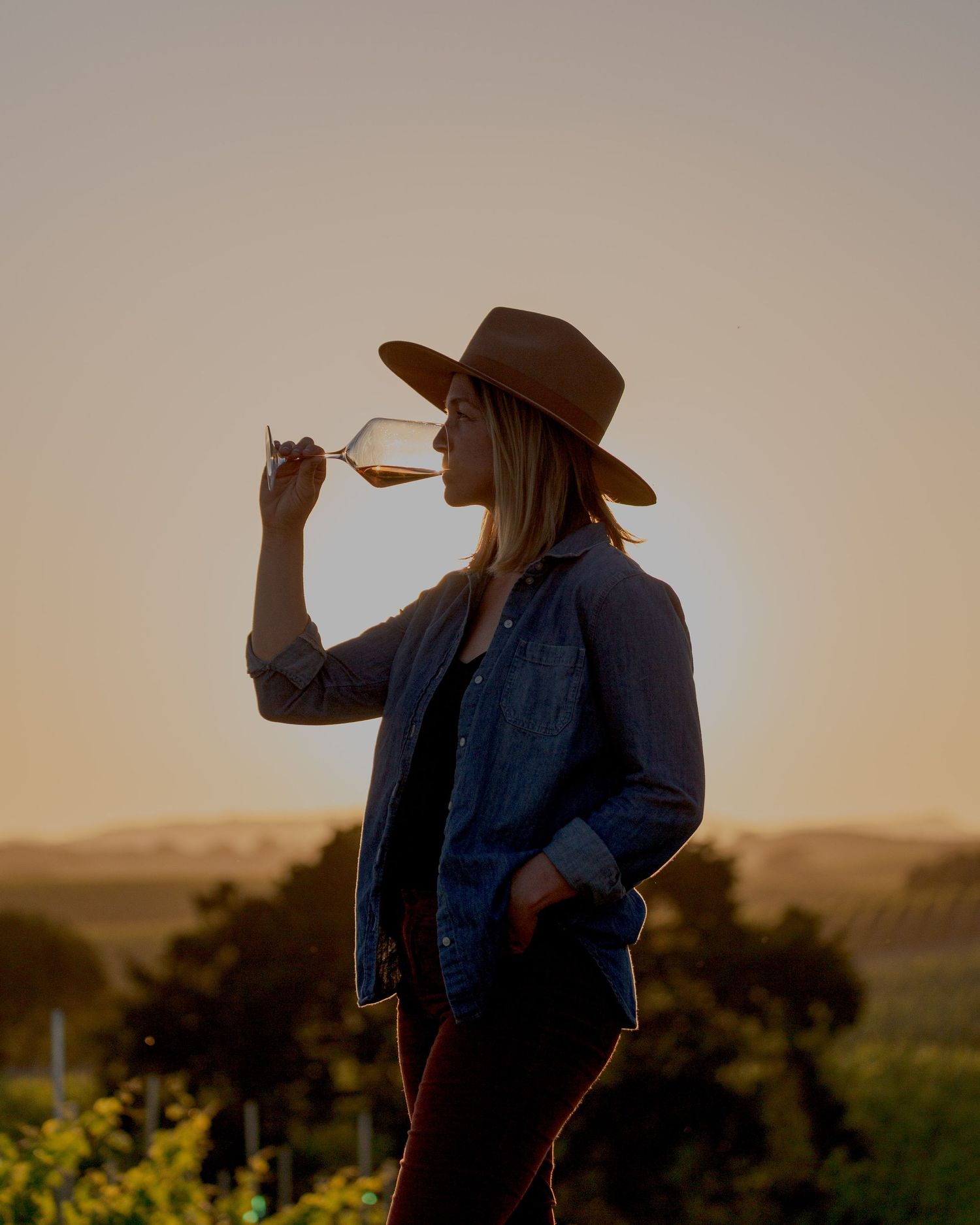 Winemaker portrait. Woman drinking wine in a vineyard at sunset in Santa Ynez, California.