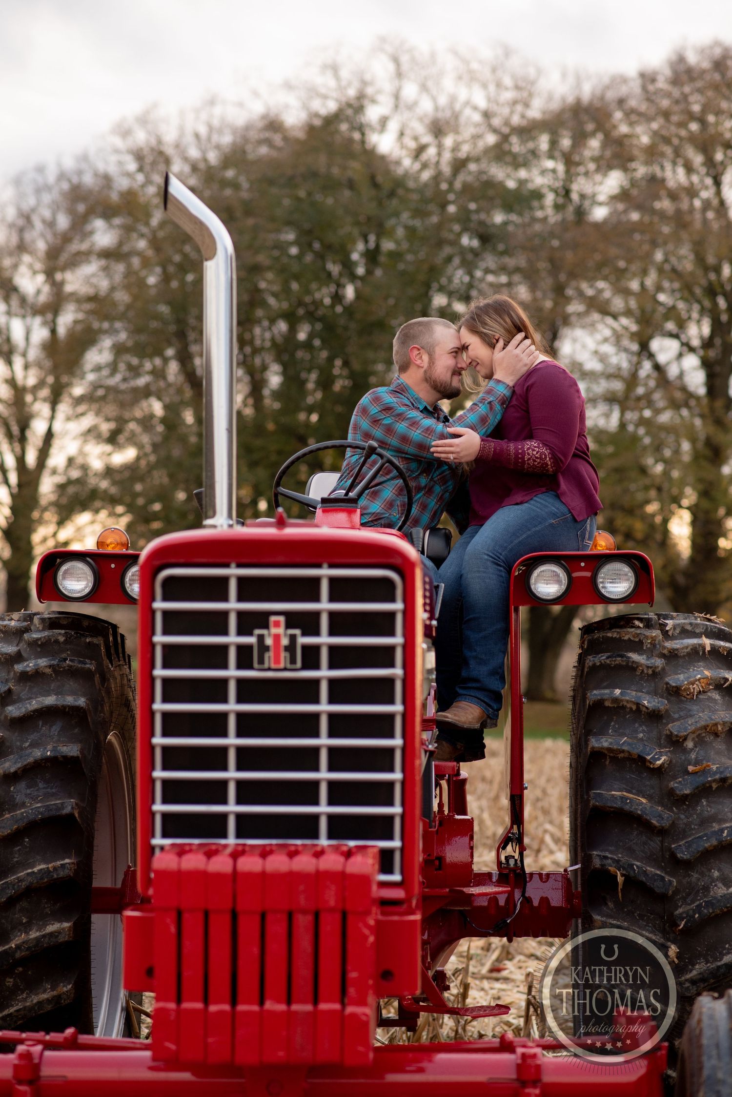 A tender moment captured on a restored red vintage tractor in a fall field.