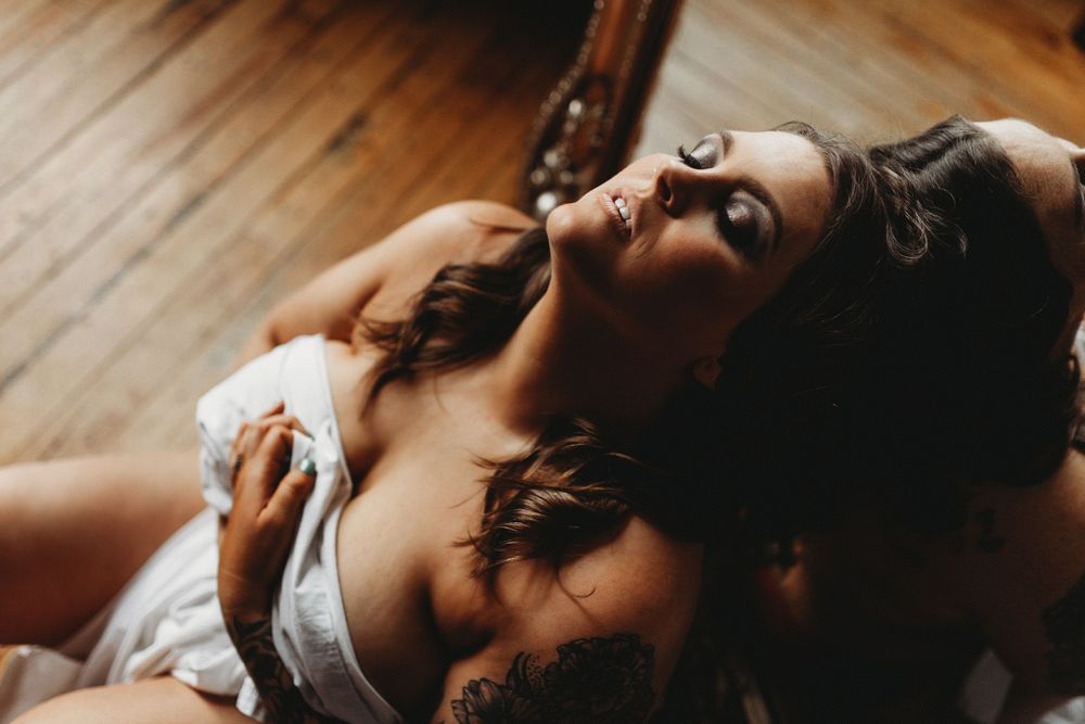 Artistic portrait with warm lighting of person reclining on hardwood floor in intimate boudoir style photography.