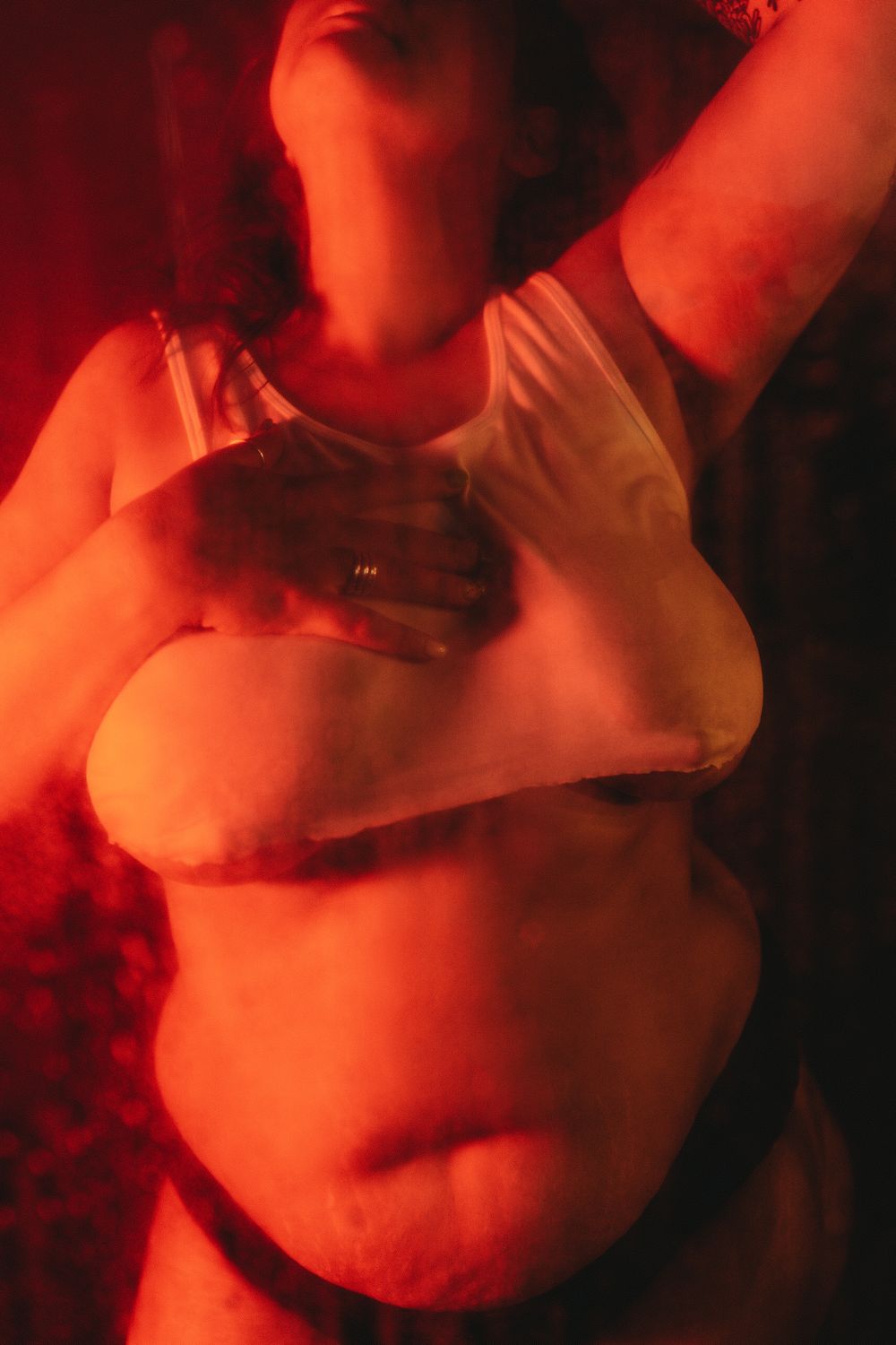 Body positive portrait with moody red lighting highlighting natural curves and form.