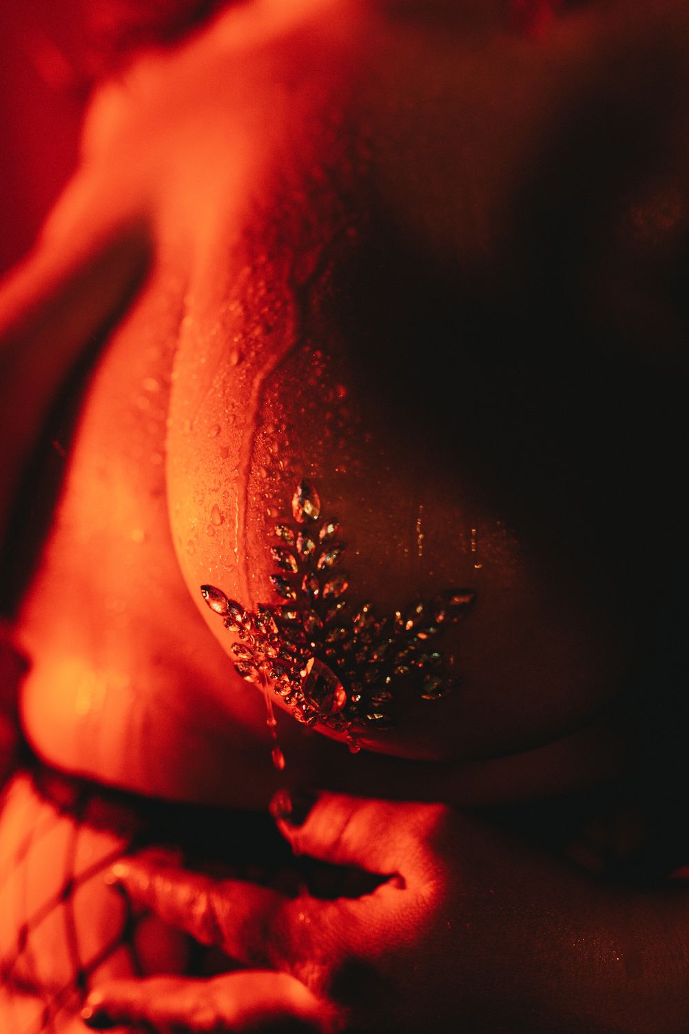 A close-up detail of red lingerie with delicate lace pattern decoration, illuminated by dramatic low-key lighting.