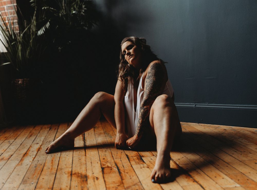 Natural light boudoir photo on wooden floor with indoor plants.